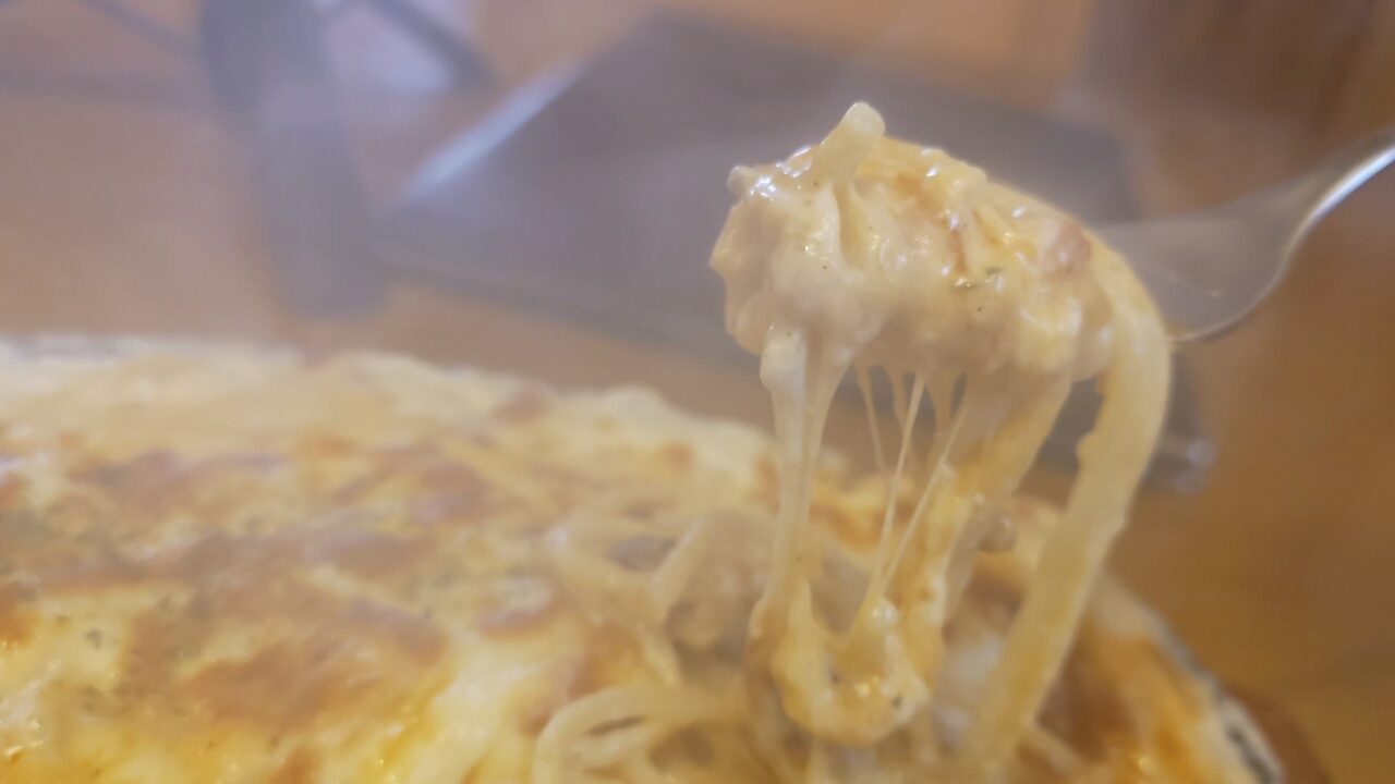 スパゲティミートグラタンのとろけるチーズをフォークで持ち上げた様子