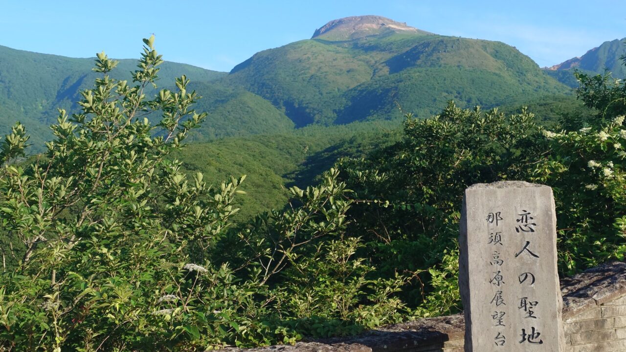 恋人の聖地と刻まれた石碑と、奥にそびえ立つ雄大な那須岳の景色（那須高原展望台）
