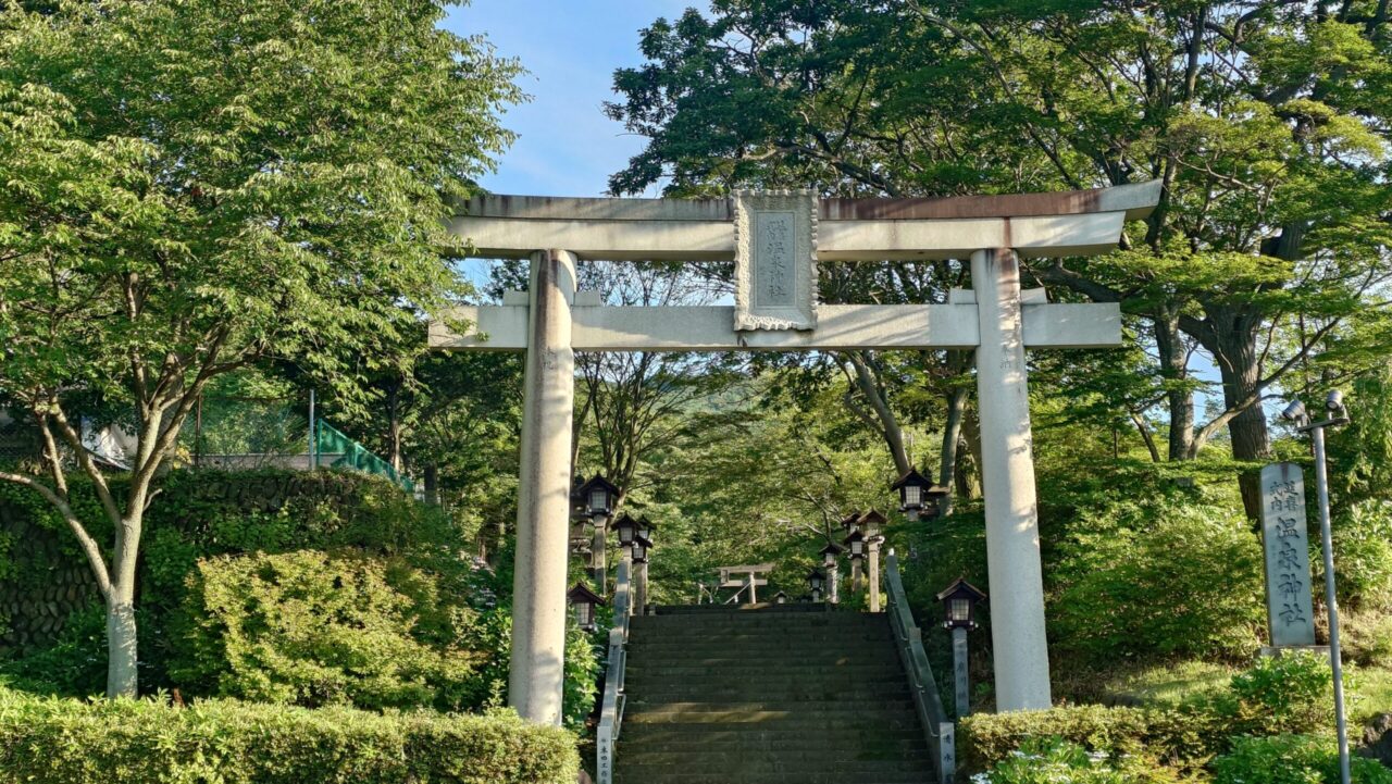 朝の澄んだ緑に囲まれた那須温泉神社（ゆぜんじんじゃ）の入り口に立つ立派な石造りの大鳥居